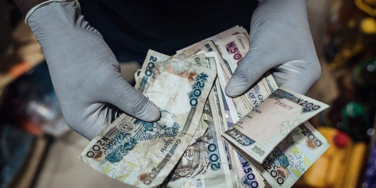 A vendor counts Nigerian naira banknotes in Abuja, Nigeria.Photographer: KC Nwakalor/Bloomberg
