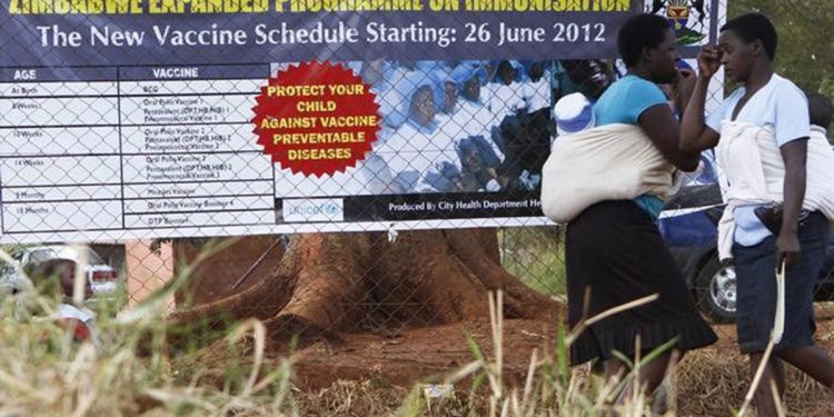 Mothers walk past a billboard encouraging immunisation against polio and measles at a clinic in Harare June 21, 2012. REUTERS/Philimon Bulawayo/File Photo