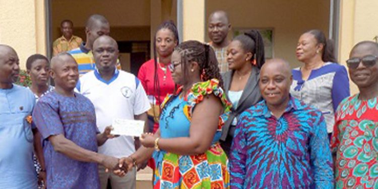 Benedicta Addo-Danquah (3rd from right) presenting the cheque to Evans Boafo, the Headmaster of ODASCO. With them are Augustus Anim Attafuah (2nd from right) and Paul Asiedu (right), a board member of the bank. Behind them are other board members of the bank.